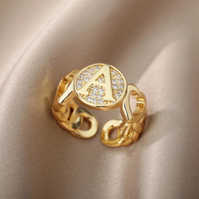 Ring mit Buchstabe in Gold zwischen zwei Herzen