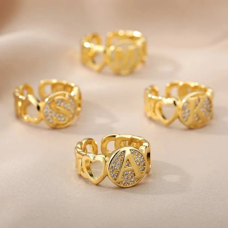 Ring mit Buchstabe in Gold zwischen zwei Herzen