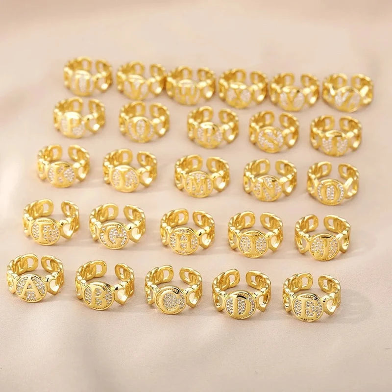 Ring mit Buchstabe in Gold zwischen zwei Herzen